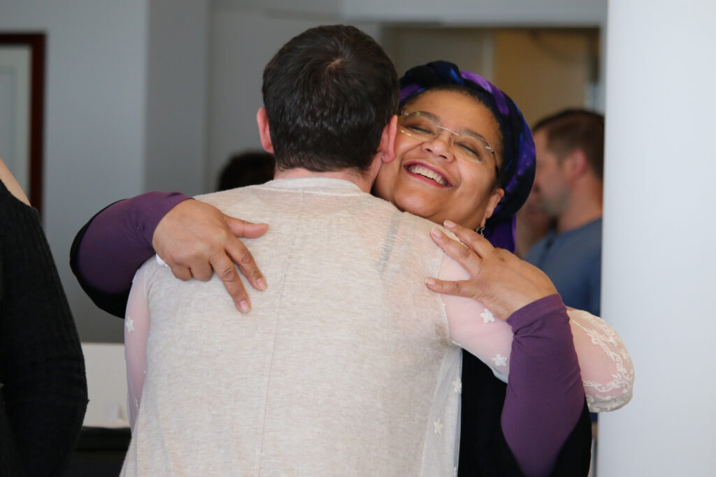 A Black female student and a white nonbinary student hugging each other