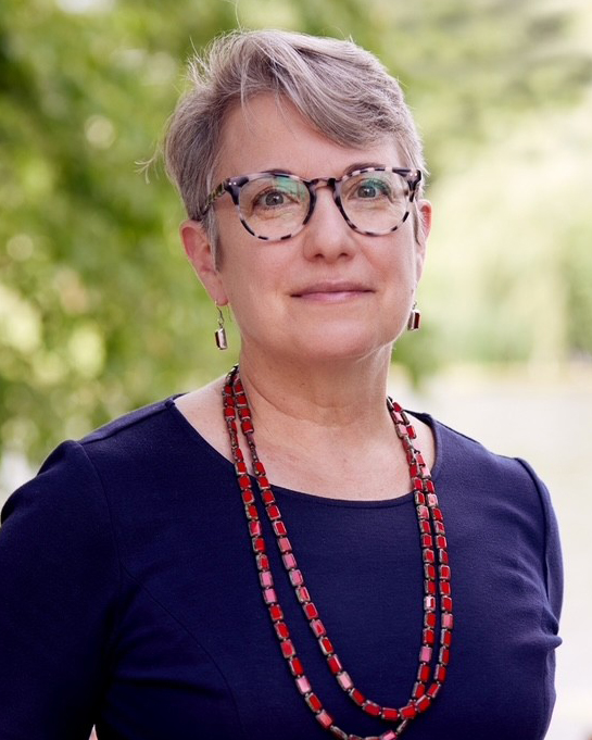 White fem-presenting person with short light-colored hair and turtle-shell glasses