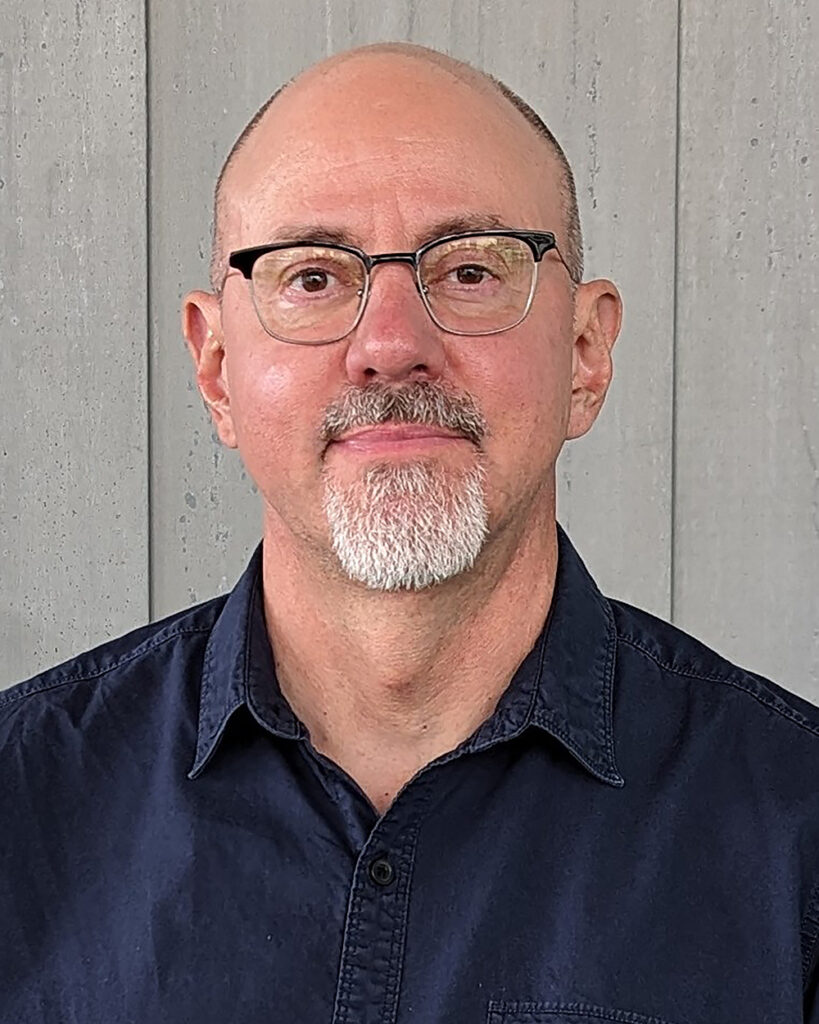 White masculine-presenting person with glasses and short, white beard