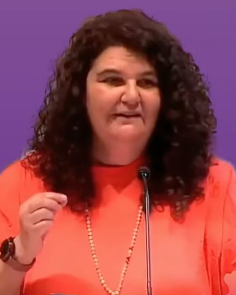 A fem-presenting person of color with long, dark, curly hair